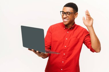Kırmızı gömlekli ve gözlüklü yakışıklı Afro-Amerikan genç adam video için laptop kullanıyor.