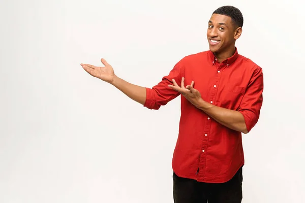 Beau jeune homme afro-américain en chemise rouge pointe paumes de côté isolé sur blanc — Photo