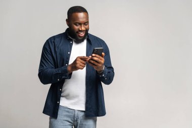 Black guy chatting online, using new mobile app, full length
