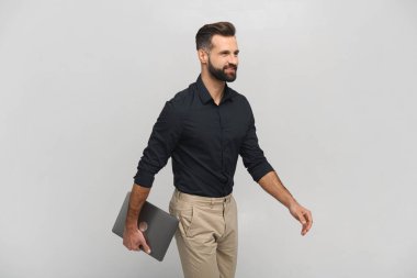 Elinde dizüstü bilgisayarla bir yere giden gülümseyen olumlu adamın portre görüntüsünü kaldır. Beyaz üzerine kapalı stüdyo çekimi.