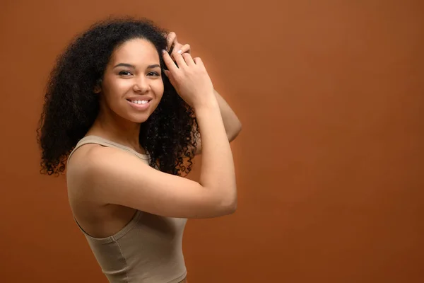 Studio portrait on the brown background of carefree serene multiracial woman looking at camera and laughs — стоковое фото