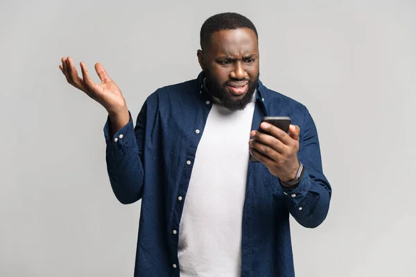 Missnöjd ung afro-amerikansk man som håller smartphone — Stockfoto