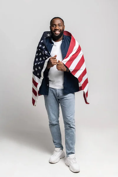 Portrait of positive muscular afro american guy covered with usa flag — стокове фото