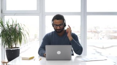 Hintli erkek çalışan kulaklık takıyor ve gözlük takıyor online danışmanlık yapıyor.