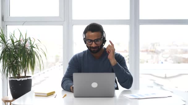 Empleado indio con auriculares y anteojos haciendo consulta en línea — Vídeos de Stock
