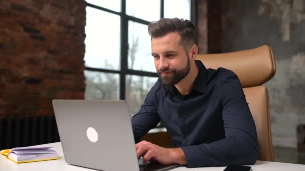 Excited caucasian man sitting at the table, looking at the laptop screen and rejoicing — стоковое видео