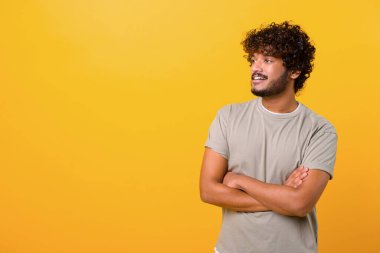 Portrait of happy satisfied handsome young Indian man in t-shirt standing with crossed arms