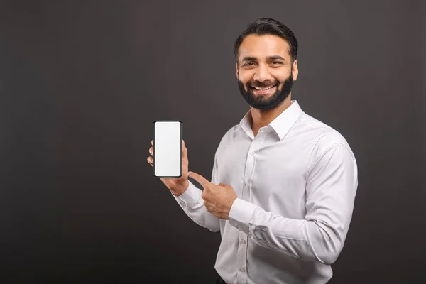 Προσομοίωση. Όμορφος με αυτοπεποίθηση γενειοφόρος Ινδός άνδρας σε επίσημη ένδυση που δείχνει smartphone με άδεια οθόνη — Φωτογραφία Αρχείου