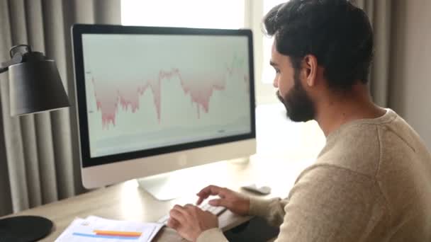 Indian male trader using computer for remote work, making cryptocurrency financial market analysis — Video Stock