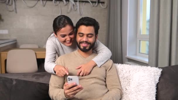 Веселая пара проводит время со смартфоном дома. — стоковое видео