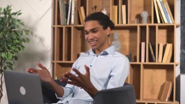 Uzaktan video bağlantısı için dizüstü bilgisayar kullanan çok ırklı komik bir adam.