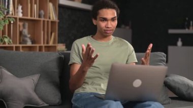 Video iletişimi. Çok ırklı genç adam video görüşmesi için dizüstü bilgisayar kullanıyor.