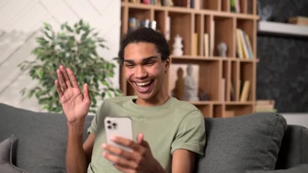 Löjlig mörkhårig man i casual wear med smartphone för virtuellt möte — Stockvideo