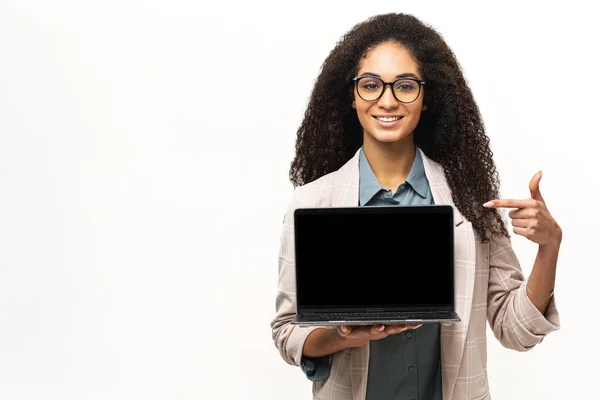 Pozitivní usmívající se žena na volné noze držení a zobrazení notebooku s prázdnou obrazovkou, spokojený multiracial žena inzerce nové počítačové aplikace izolované na bílém pozadí — Stock fotografie