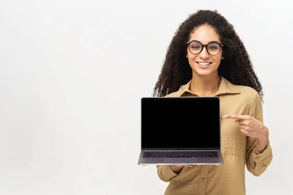 Satisfait femme multiraciale publicité nouvelle application informatique isolé sur fond blanc, maquette. Positif souriant femme pigiste tenant et montrant ordinateur portable — Photo