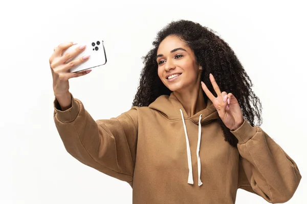 Glad bekymmerslös afroamerikansk ung kvinna med lockigt hår tar selfie på smartphone, spela in videomeddelande, streaming i sociala medier — Stockfoto
