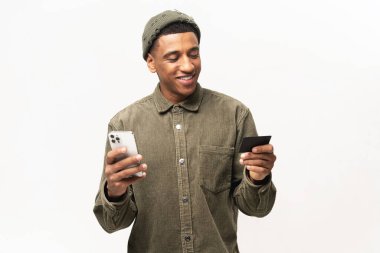 Neşeli Orta Doğulu adam online alışveriş için akıllı telefon ve kredi kartı kullanıyor. Mutlu adam internetten yemek sipariş ediyor. Erkek, uzun zamandır beklenen cep telefonunun parasını ödüyor.