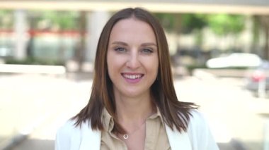 Gülümseyen kadın girişimci, küçük işletme sahibi, şehir merkezinde kasıtlı kadın ofis çalışanı, sokakta şık giyinmiş, iş kadını kameraya bakıyor.