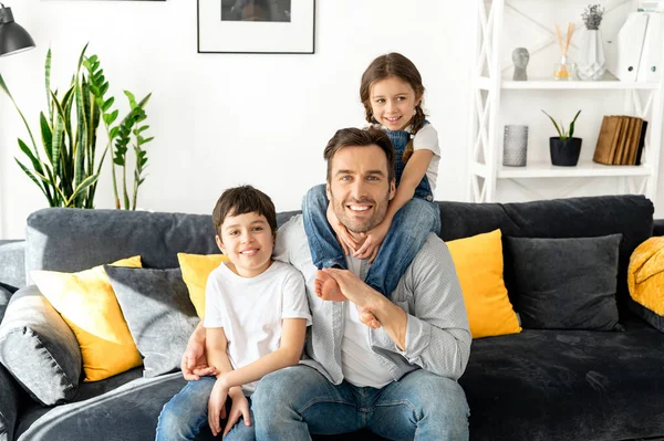 一个快乐的多种族家庭的画像 儿子和蹒跚学步的女儿坐在舒适的客厅沙发上 看着相机 在家里享受周末 — 图库照片