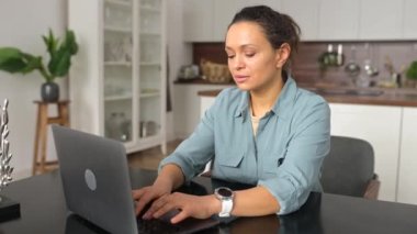 Serbest çalışan kadın, acı çeken yüz ifadesiyle baş şakaklarına masaj yapıyor. İnternette çalışan bir kadının dizüstü bilgisayarının başında oturmaktan yorgun ve yıpranmış bir şekilde baş ağrısı çekiyor.