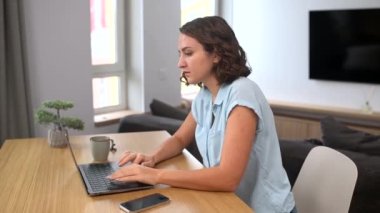 Ev ofisinin masasında dizüstü bilgisayar kullanan, e-postalara cevap veren, klavyeye yazı yazan konsantre kadın serbest çalışan.