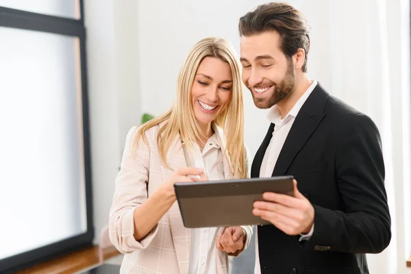 Modern man and woman in formal wear using digital tablet at the office. Portrait of male and female office employee using online computer app for accounting