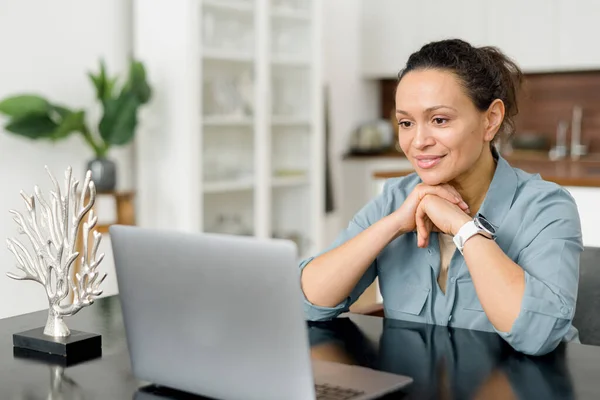 Intelligent businesswoman using a laptop in the office. Smart woman entrepreneur looks through emails, analyses tasks, checks report. Middle aged online teacher conducts lecture