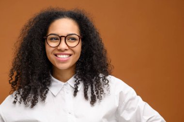 Neşeli genç bayan izole edilmiş kahverengi arkaplan. Genç, çok kültürlü, dişlek kadın boş bir alanda duruyor.