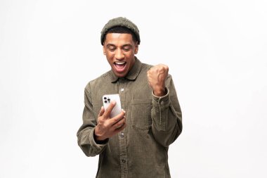 Heyecanlı, çok kültürlü bir adam, kameraya bakıyor ve elinde telefonuyla bağırıyor. Şaşırmış duygusal açıdan şanslı bir adam ağzı açık, iyi bir mesajla sevinen, iyi haber, piyangoyu kazandı.