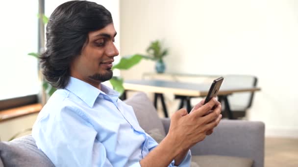 Serene Ung Indian Man Håller Smartphone Sitter Soffan Hemma Östra — Stockvideo