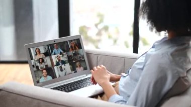 Bilgisayarın başında oturan çok ırklı bir kadının görüntüsü, video toplantısı yoluyla arkadaşlarıyla sohbet etmesi, yeni projeyi tartışması, online öğretmenlik yapması, çeşitli insanlarla video görüşmesi yapması.