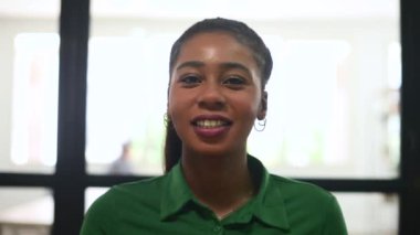 Çekici bir Afro-Amerikalı iş kadınının portresi. Yeşil, şık, rahat gömlekli, gülümseyen ve kameraya konuşan bir kadın. Video çağrısı sırasında webcam görünümü