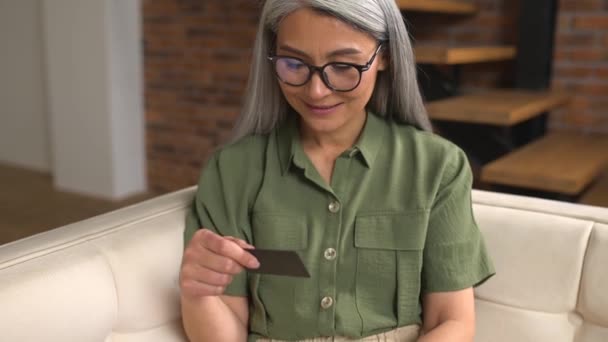 Spokojny Starszy Businesswoman Okularach Siedzi Kanapie Pomocą Laptopa Karty Kredytowej — Wideo stockowe