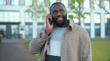 Kaygısız Afro-Amerikalı açık havada rahat rahat konuşan sakin bir adam sokakta yürürken telefonla konuşmaktan zevk alır.
