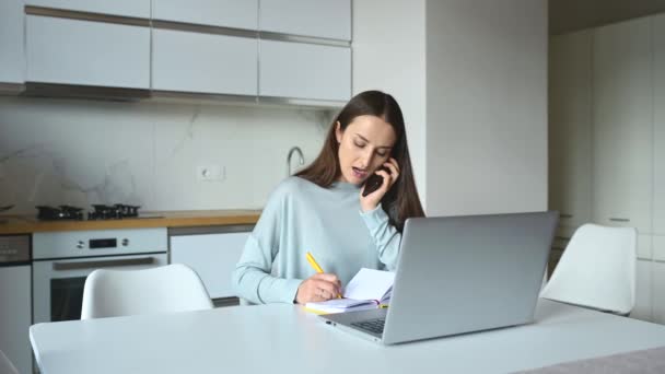 Multitask Freelance Woman Talks Smartphone Takes Notes Pen Using Laptop — Stock Video