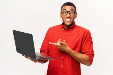 Şok olmuş bir adamın elinde dizüstü bilgisayarla kameraya şaşkın şaşkın bakışlarının portresi. Beyaz arka planda izole edilmiş kapalı stüdyo görüntüleri