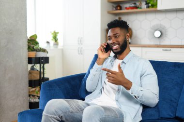 Akıllı tişörtlü, akıllı telefondan konuşan ve kameraya bakan çok kültürlü iş adamının vesikalığı. Hoş bir telefon konuşması yapan adam.