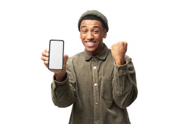 Akıllı telefonu tutan ve gülümseyen mutlu adam evet hareketi yapıyor, çevrimiçi piyangoyu kutluyor ya da zaferi ele veriyor. Beyaz arka planda izole edilmiş kapalı stüdyo görüntüleri