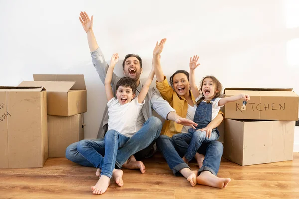 Overjoyed Multiracial Family Four Sitting Floor Surrounded Cardboard Boxes Empty — Stock Photo, Image