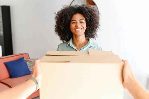 Delivery direct in hands. POV courier giving a delivery box to a smiling african-american female customer, happy satisfied multiracial woman glad to fast shipping, taking parcel