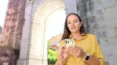 Woman tourist uses navigator on the smartphone, using mobile app for travelers, watching at online mobile maps in her phone, looking for destination