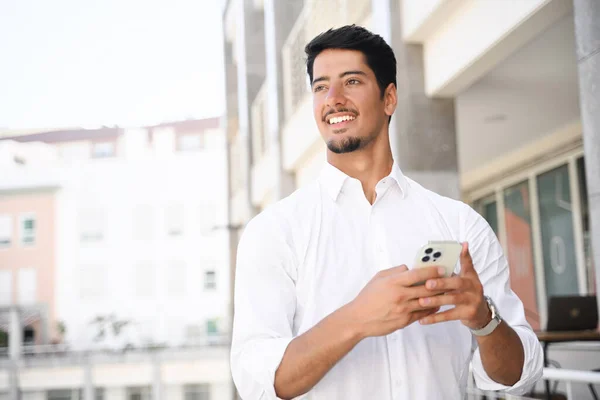 Счастливый Улыбающийся Латинский Темноволосый Мужчина Белой Рубашке Помощью Смартфона Улице — стоковое фото