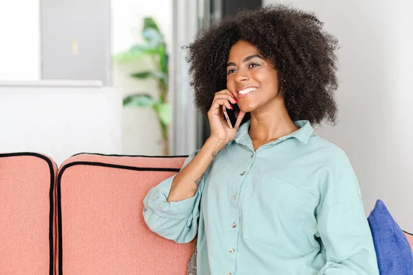 Щаслива Афро Американка Спілкується Смартфоні Сидячи Дивані Вдома Насолоджуючись Приємною — стокове фото