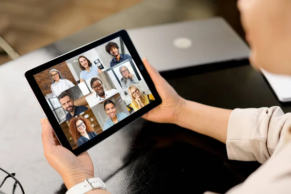 Woman participates in video conference with multiracial team, virtual meeting on the digital tablet, e-learning. Female employee talking online with group of diverse colleagues or work team