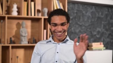 Yakışıklı adam video bağlantısı için dizüstü bilgisayar kullanıyor, gerçek aramalar yapıyor, uzun zamandır beklenen toplantılar yapıyor, işaret ediyor, bilgisayar ekranına bakıyor, kanepede oturuyor ve dizüstü bilgisayarını dizlerinde tutuyor.