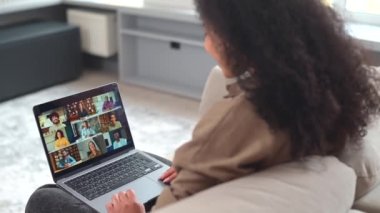 Dizüstü bilgisayarın üstünden çeşitli çalışanlarla, ekrandaki iş arkadaşlarıyla video görüşmeleri, online toplantılar. Birçok insanla video konferansı için uygulamayı kullanan çok ırklı bir kadın.