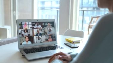 Dizüstü bilgisayardaki video konferansına katılan bir grup insan. Çok ırklı ekiple video bağlantısı için bilgisayar uygulaması kullanan kadın, çevrimiçi olarak tartışıyor, uzaktan takım çalışması