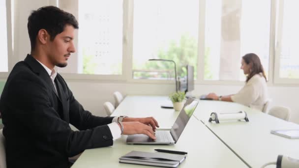 事務所の人たちは一緒に働いている 現代の同僚スペースでラップトップを使用してフリーランス 前景にスマート集中男性従業員 — ストック動画