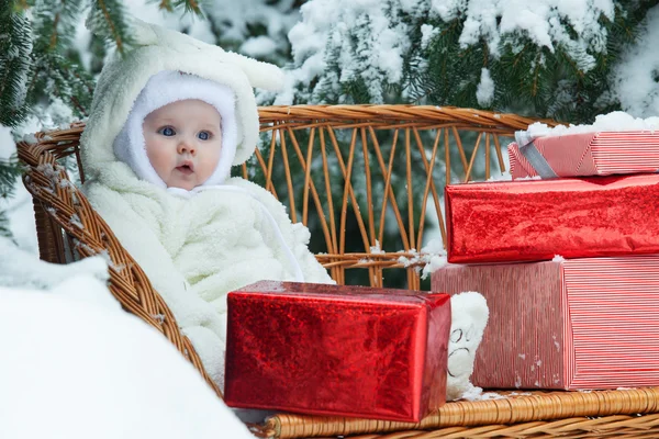 Christmas baby with gift on vinewoven bench — Stock Photo, Image