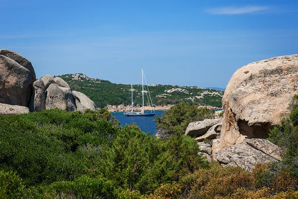 Båt med suddiga paraglida bakom klipporna — Stockfoto